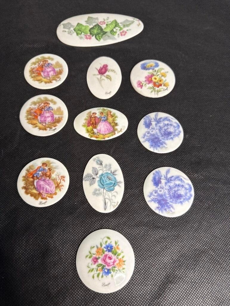 A collection of round and oval Limoges porcelain brooches with courting couples, roses and blue flowers