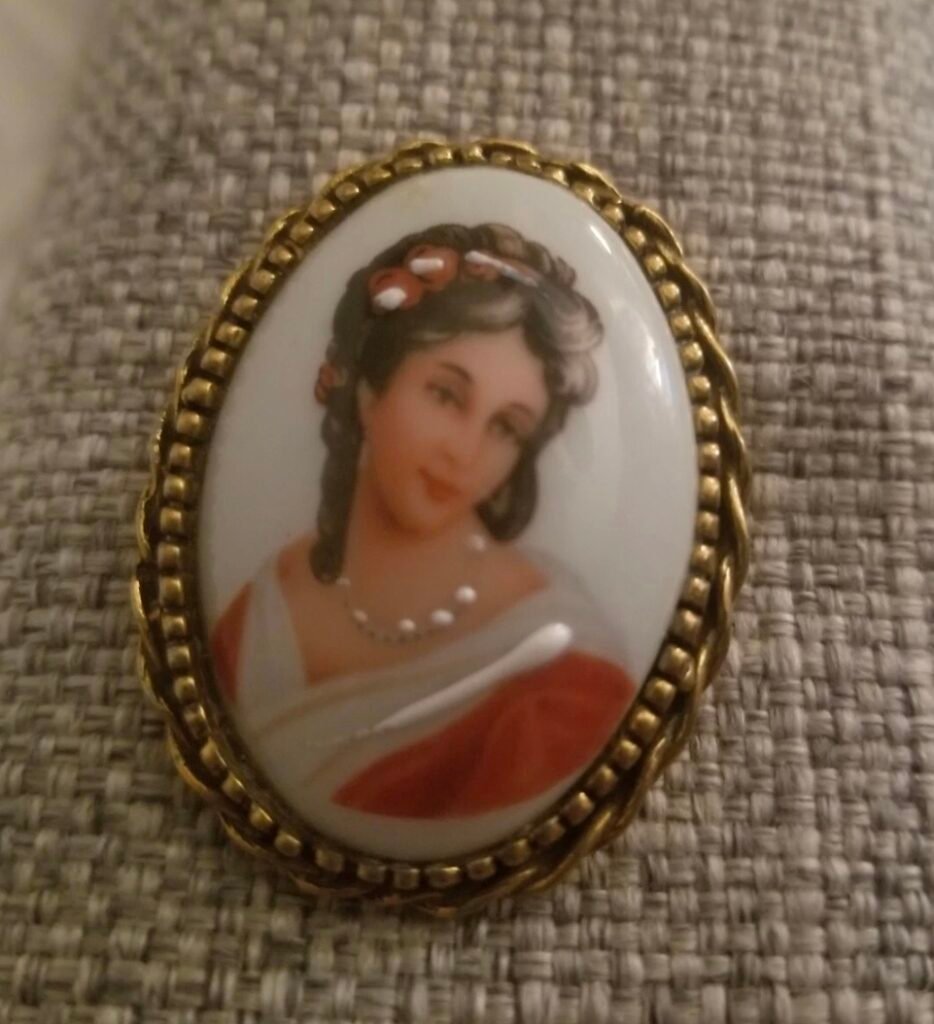 Oval porcelain portrait brooch of a young woman with flowers in her hair, in a gilt rope frame