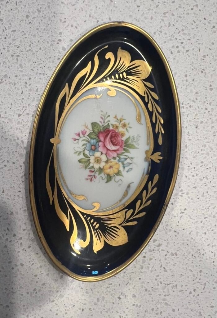 Oval porcelain tray with a cobalt border, bold gold leaf scrolls and a central bouquet of roses