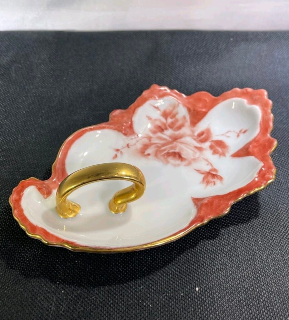 Porcelain leaf dish with coral rose decoration, coral-tinted rim and a gold loop handle