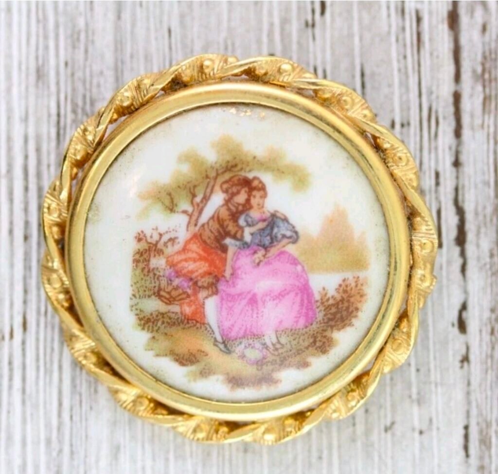 Round porcelain brooch with a courting couple in a twisted gold frame