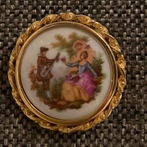 Round porcelain brooch with a guitar player and lady, in a twisted gold frame