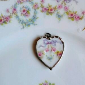 Heart-shaped pendant cut from floral porcelain with a lilac bow and pink roses, in a silver-tone frame