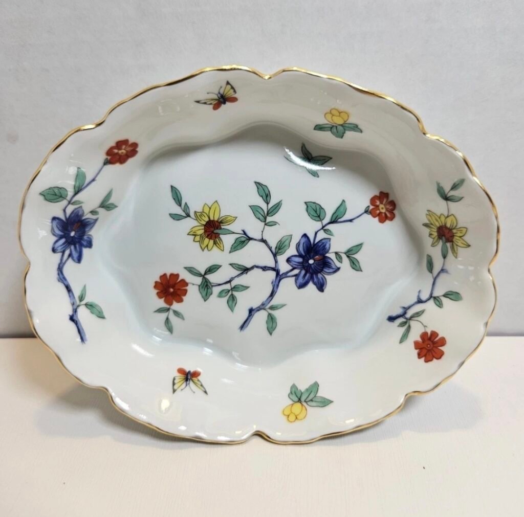 Scalloped oval porcelain dish with blue, red and yellow flowers on branches and butterflies, with a gold rim