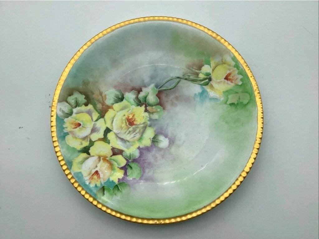 Hand-painted porcelain bowl with yellow roses on a soft green ground and a beaded gold rim
